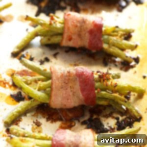 Bacon wrapped green beans baking on a sheet in the oven.
