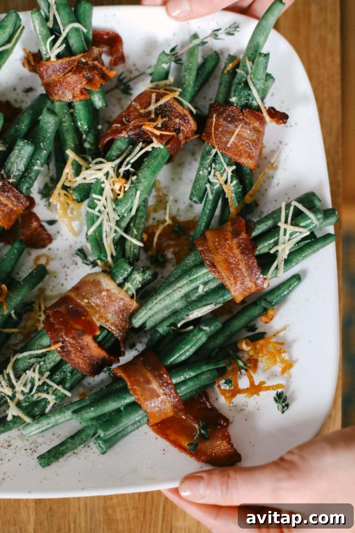Plate of finished bacon wrapped green beans topped with fresh parmesan cheese
