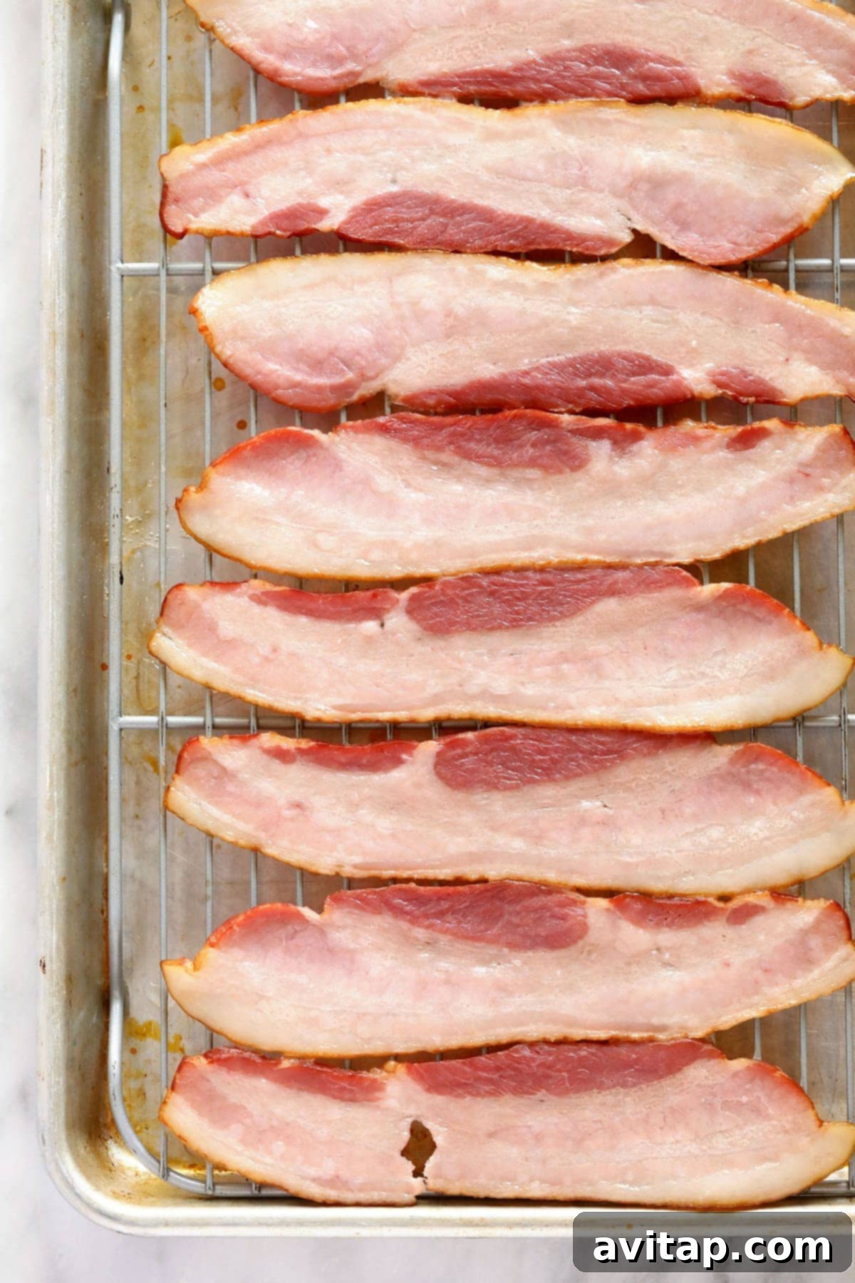 Raw thick-cut bacon strips laid out on a wire rack for pre-baking