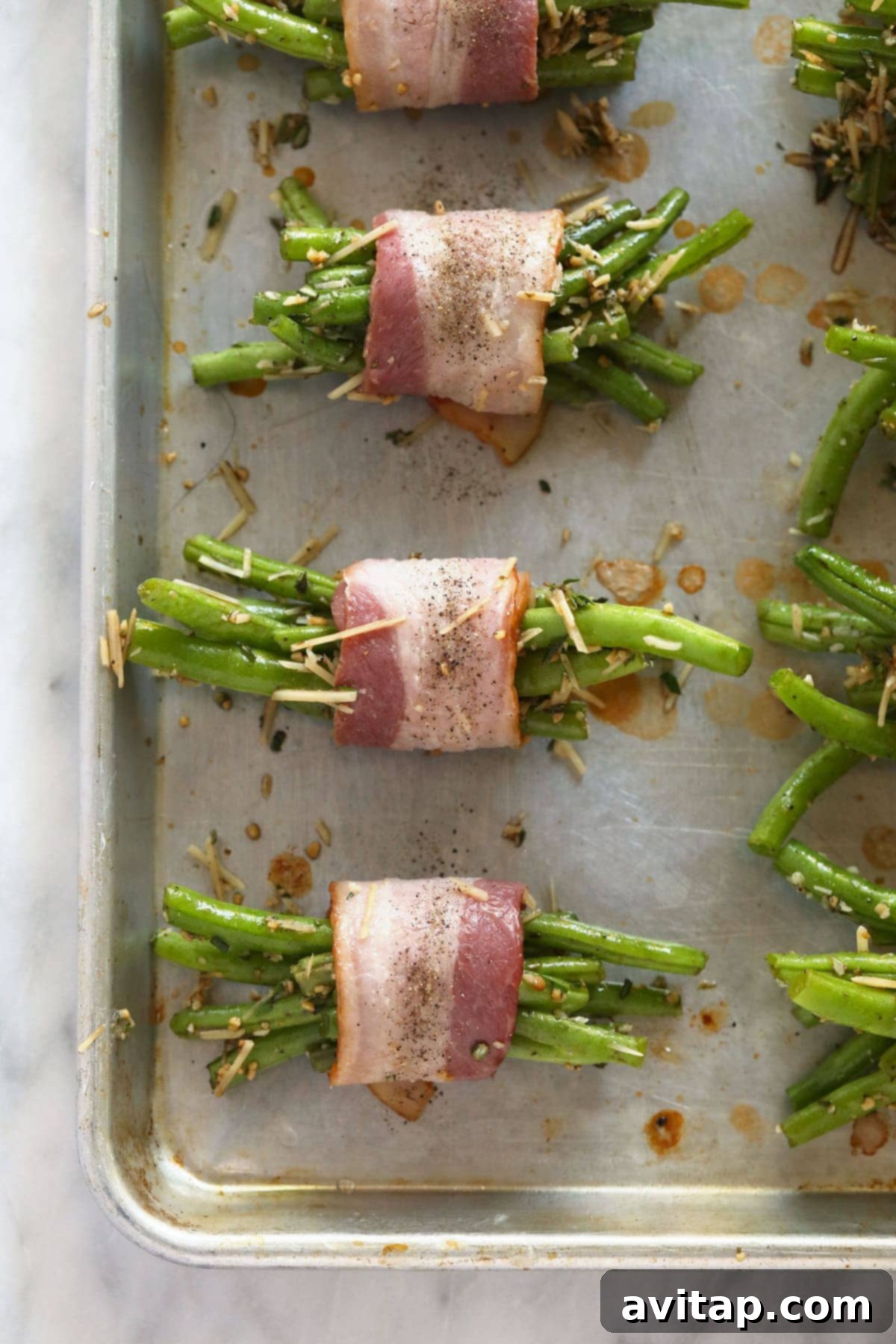 Bacon wrapped green bean bundles arranged neatly on a baking sheet, ready for the oven