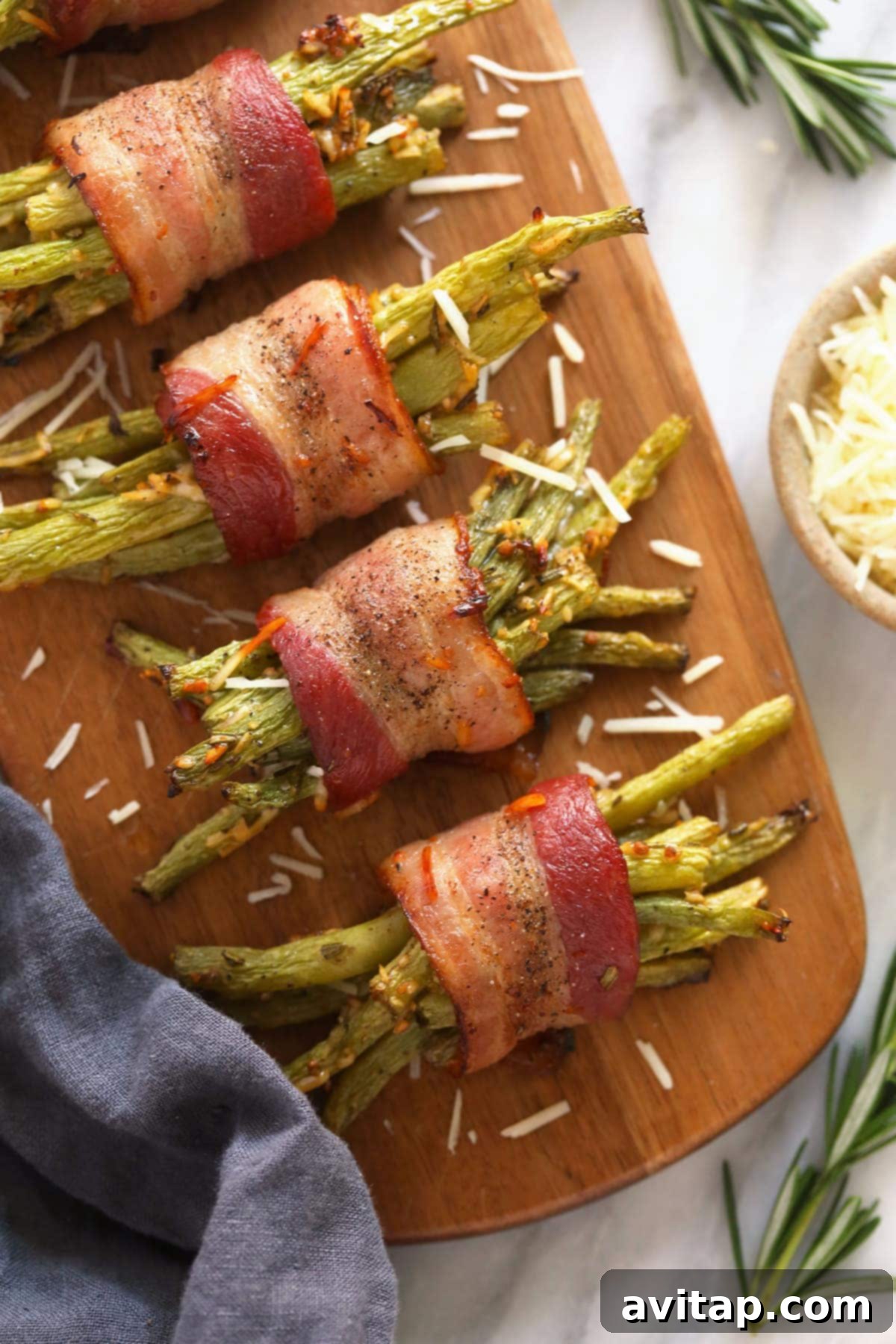 A wooden platter filled with several servings of cooked bacon wrapped green beans, garnished and ready for dining