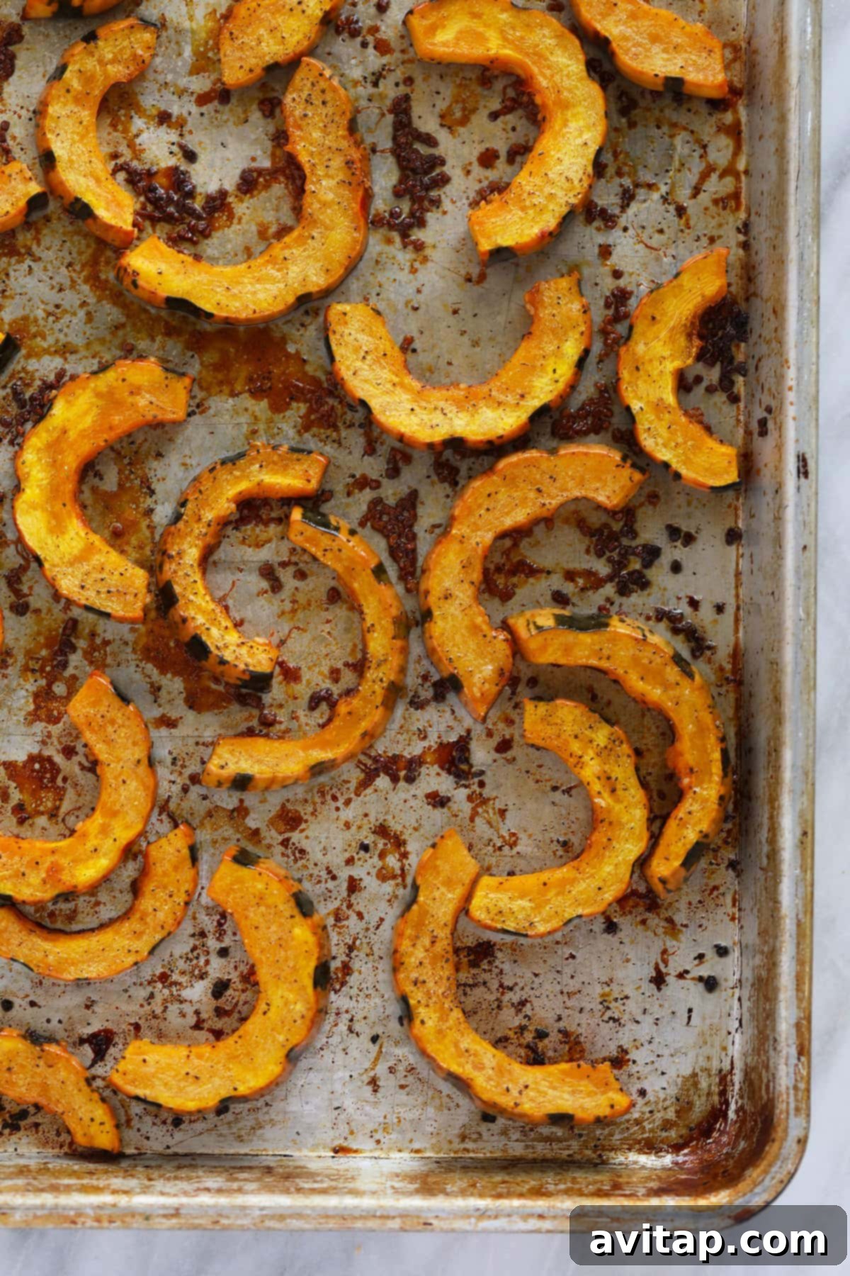 Perfectly roasted delicata squash slices, golden and tender, arranged neatly on a baking sheet, ready to be served.