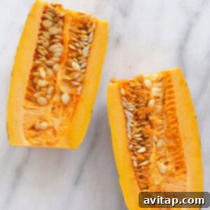 Two neatly sliced delicata squash halves on a marble surface, with seeds scooped out.