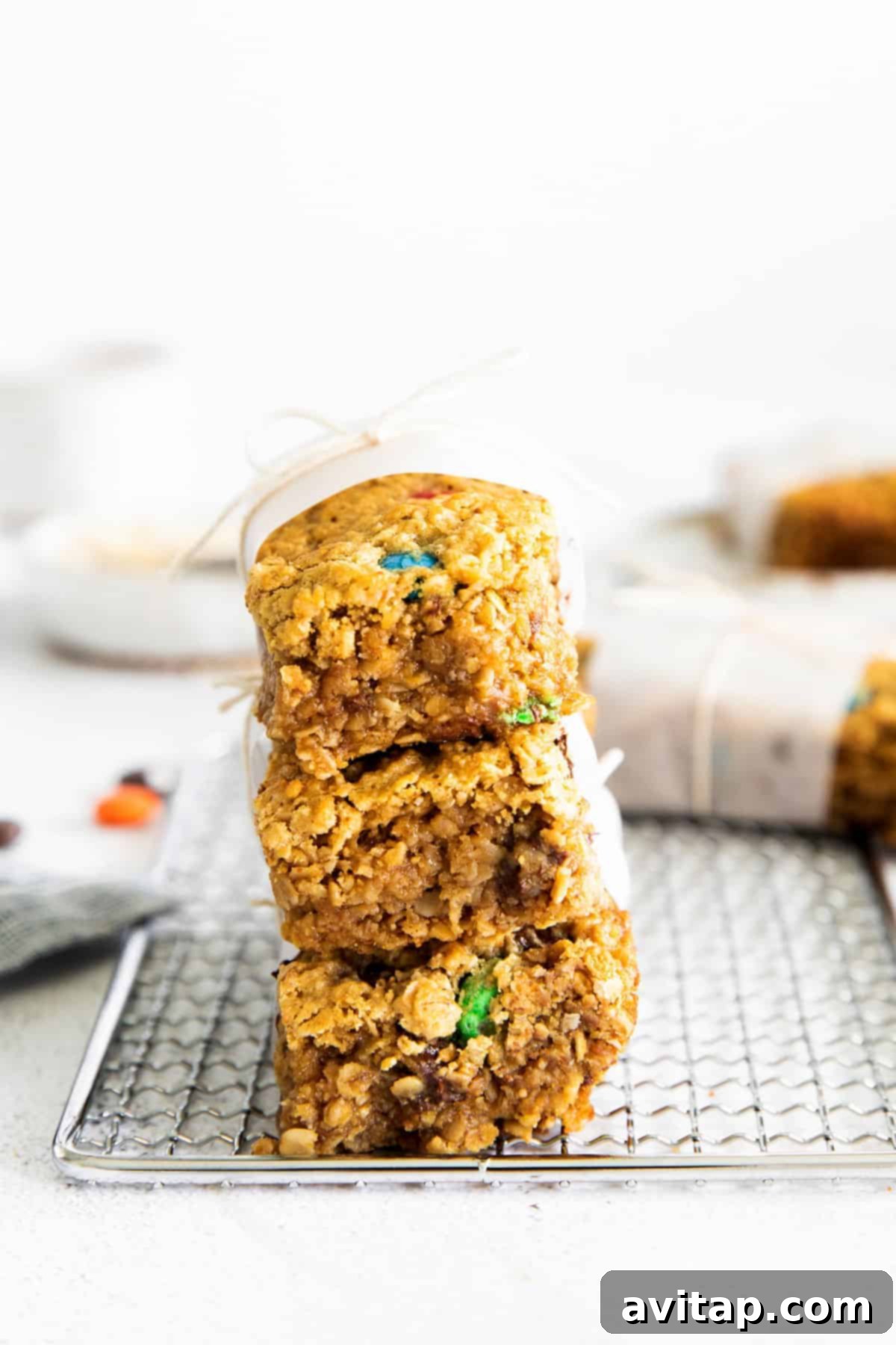 A stack of perfectly baked and sliced flourless monster cookie bars, showing off their chewy texture and colorful mix-ins.