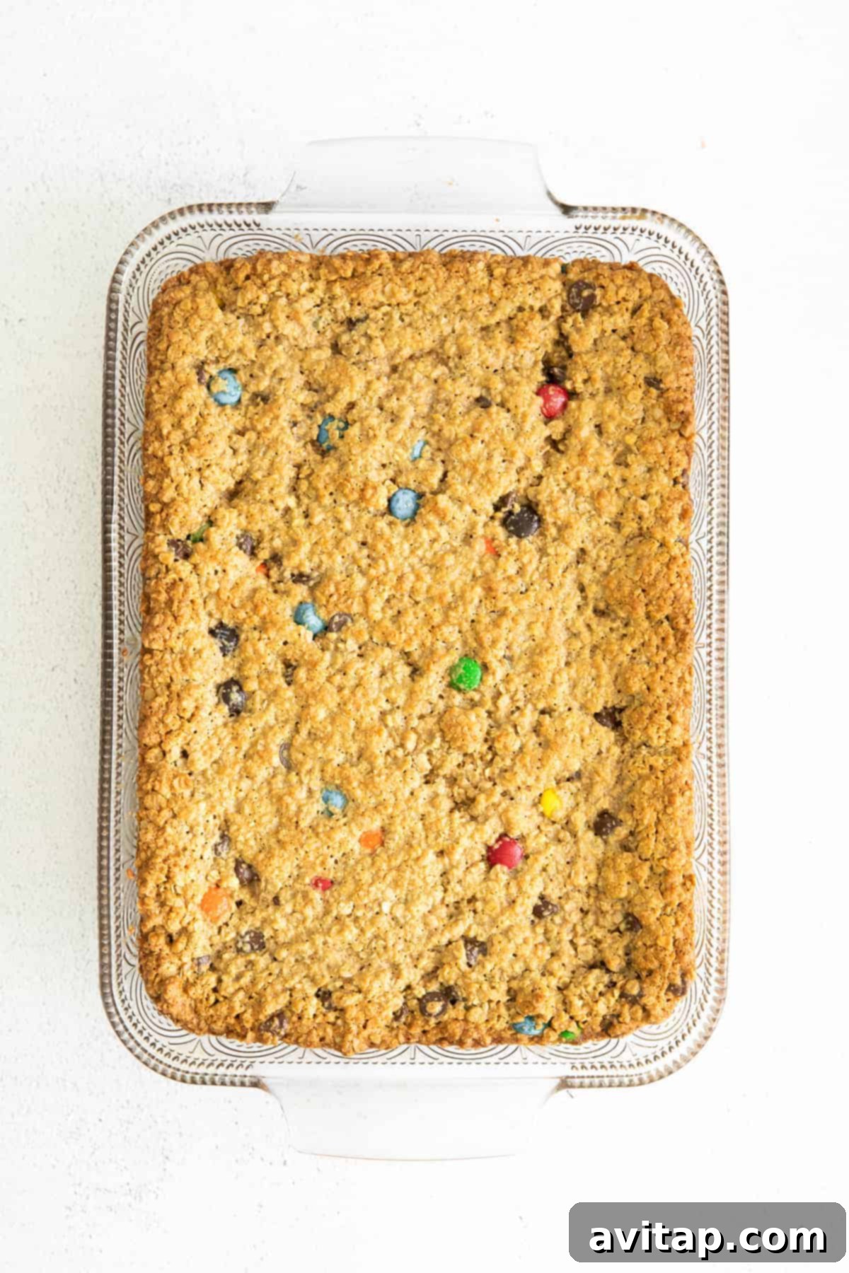 Freshly baked monster cookie bars, golden brown with visible M&M's and chocolate chips, cooling in a 9x13-inch baking dish.