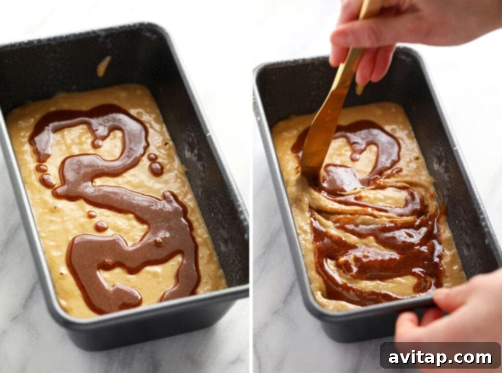 A close-up view of the process of adding a cinnamon swirl to the middle layer of banana bread batter within a loaf pan, showing distinct lines of cinnamon.