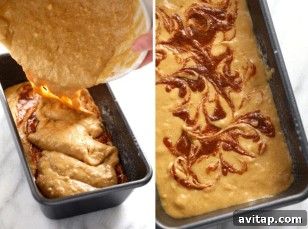 The second layer of banana bread batter being poured over the cinnamon swirl in a loaf pan, smoothing the top before the final swirl.