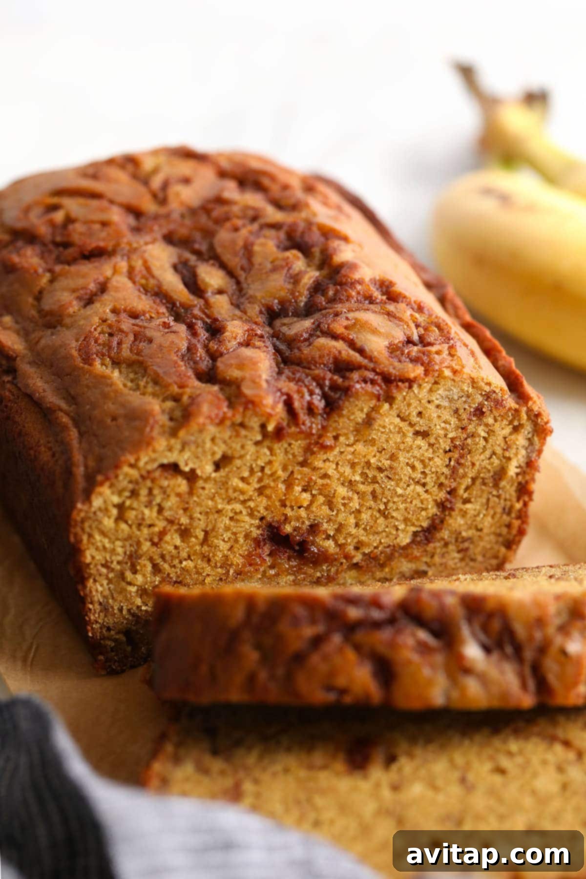 Several perfectly cut slices of cinnamon swirl banana bread arranged on a parchment-lined cutting board, highlighting their tender texture and visible swirls.