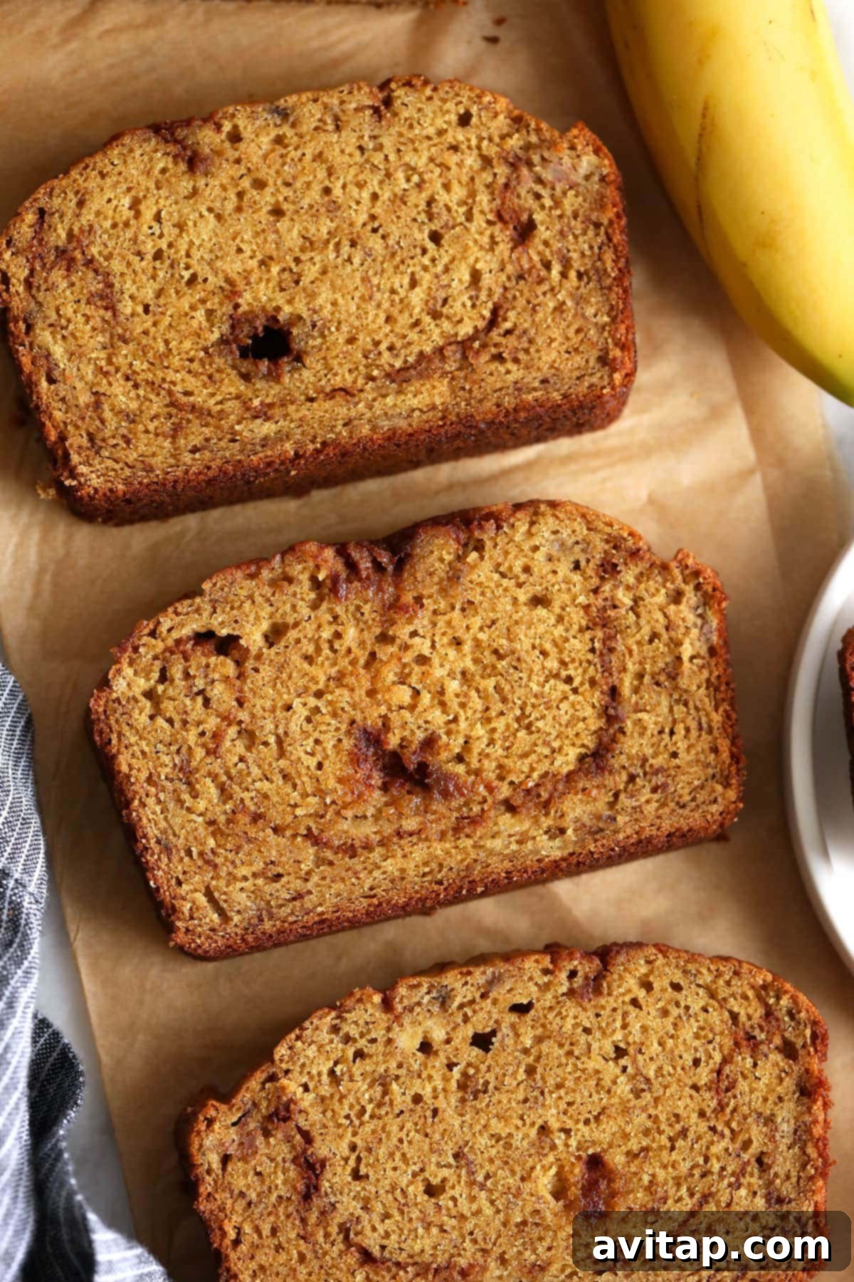 Close-up of freshly cut slices of cinnamon swirl banana bread arranged on parchment paper, ready for serving or storage.