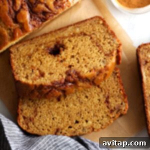 A beautiful full loaf of cinnamon swirl banana bread resting on a cutting board, ready to be sliced and enjoyed.