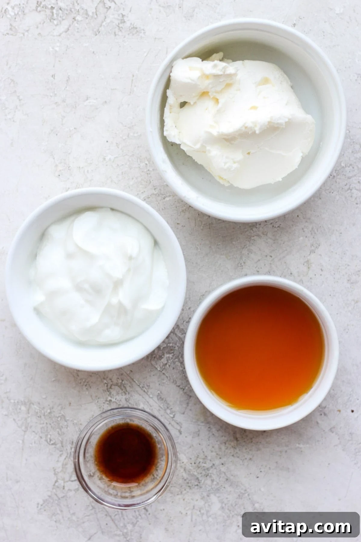 Guilt-Free Cream Cheese Frosting 2 All four simple ingredients for healthy cream cheese frosting – cream cheese, Greek yogurt, maple syrup, and vanilla extract – neatly arranged in individual bowls.