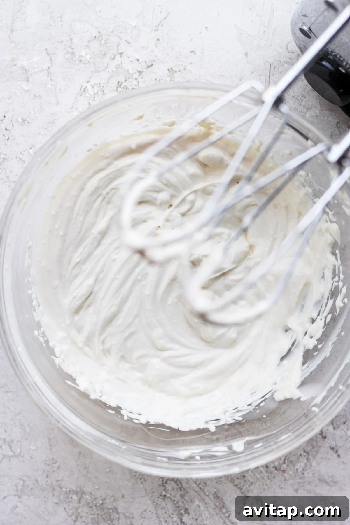 Achieving perfect consistency with a hand mixer A hand mixer blending the creamy ingredients in a bowl, creating a smooth, fluffy healthy cream cheese frosting.