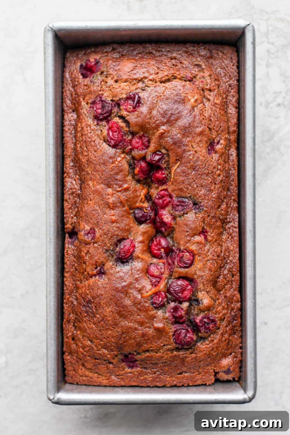 Freshly baked cranberry orange bread in a loaf pan, golden brown and inviting.