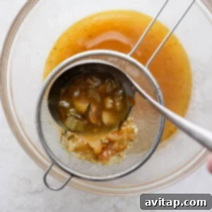a person pouring a sauce into a strainer.