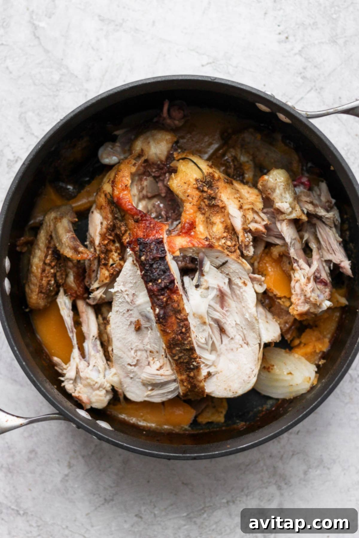 Chicken carcass, vegetables, and herbs simmering in a large pot, forming the base of a rich homemade broth.