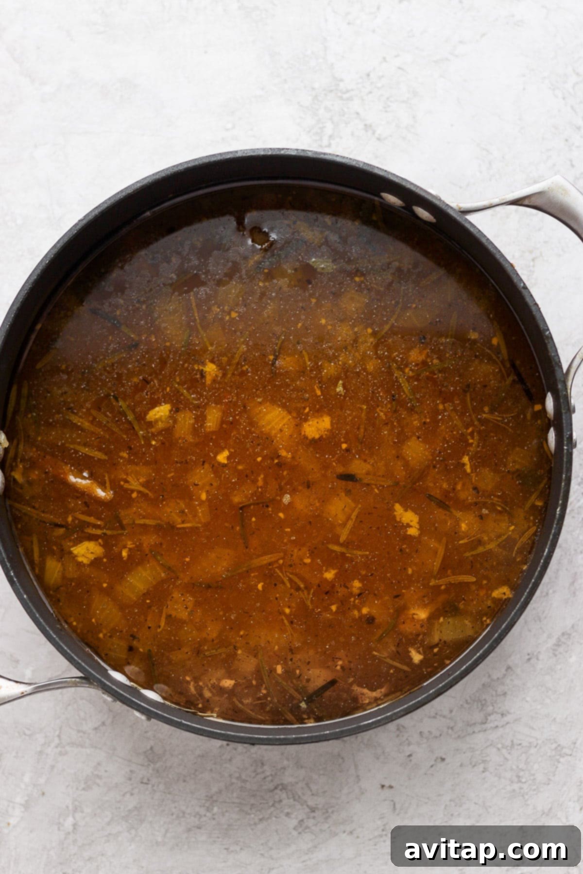 A large pot filled with freshly made, aromatic chicken broth, ready to be ladled and stored.