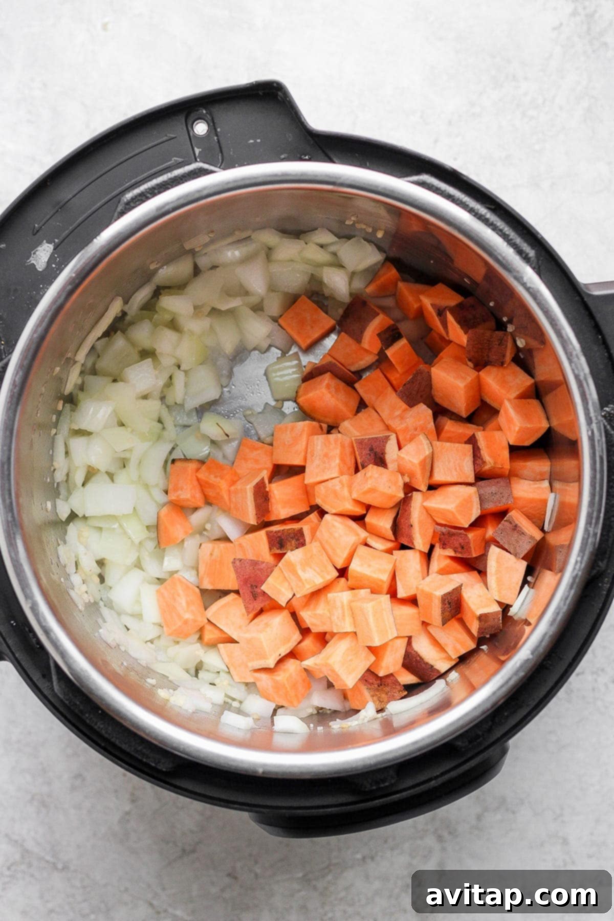 Hearty Instant Pot Lentil Soup 3 Diced sweet potatoes and minced onion sautéing in an Instant Pot pot.