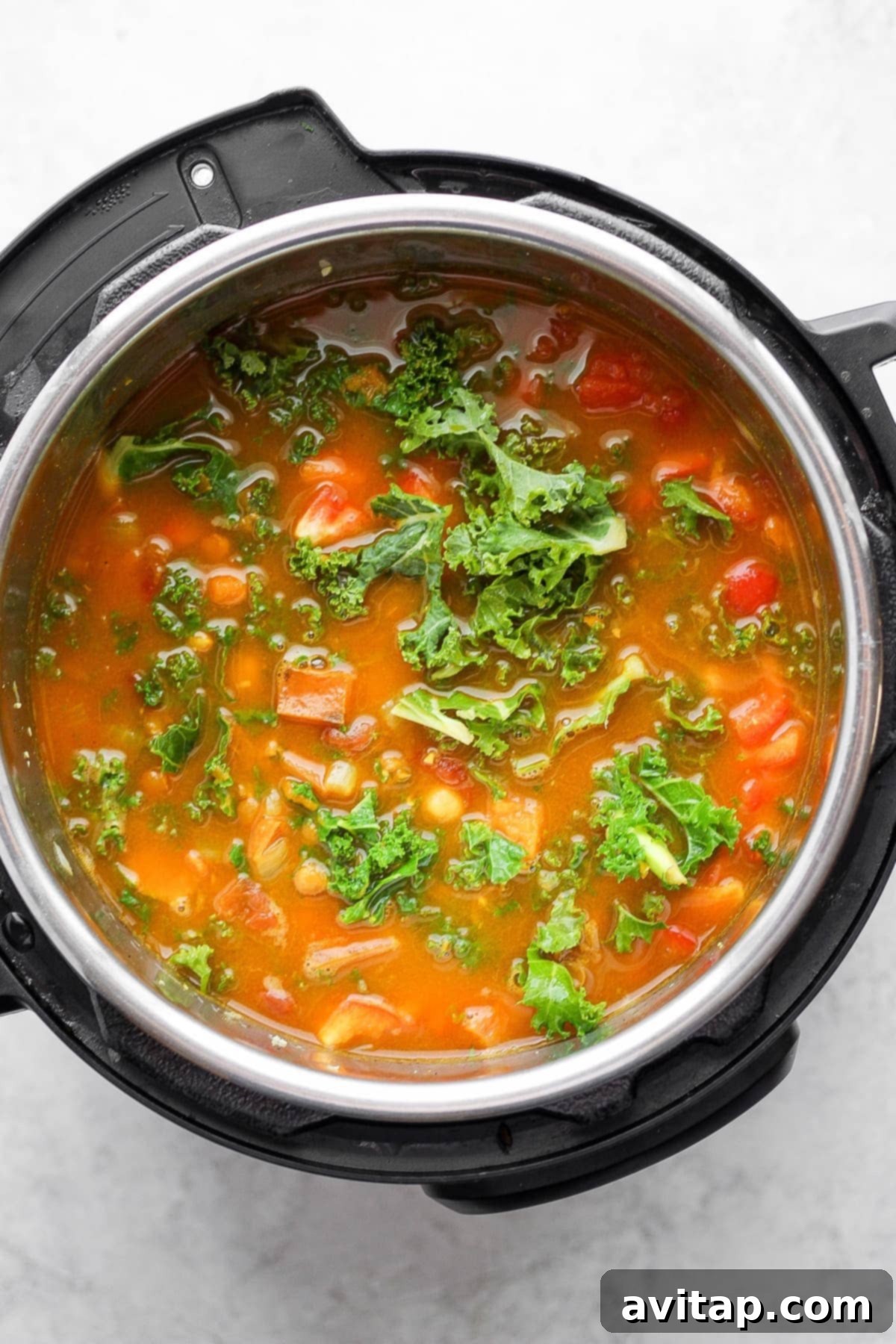 Hearty Instant Pot Lentil Soup 6 A bowl of Instant Pot lentil soup topped with fresh kale and red pepper, garnished for serving.