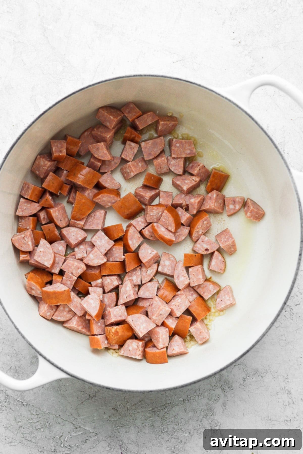 Smoky andouille sausage browning in a Dutch oven, releasing its rich flavors to create the foundation of our red beans and rice.