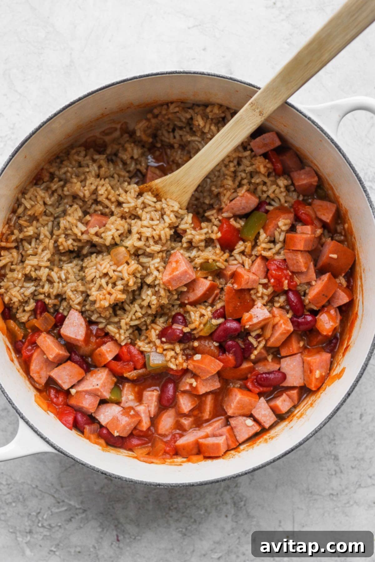 A large pot of cooked red beans and rice ingredients, ready for a final stir and serving. The textures and colors promise a comforting meal.