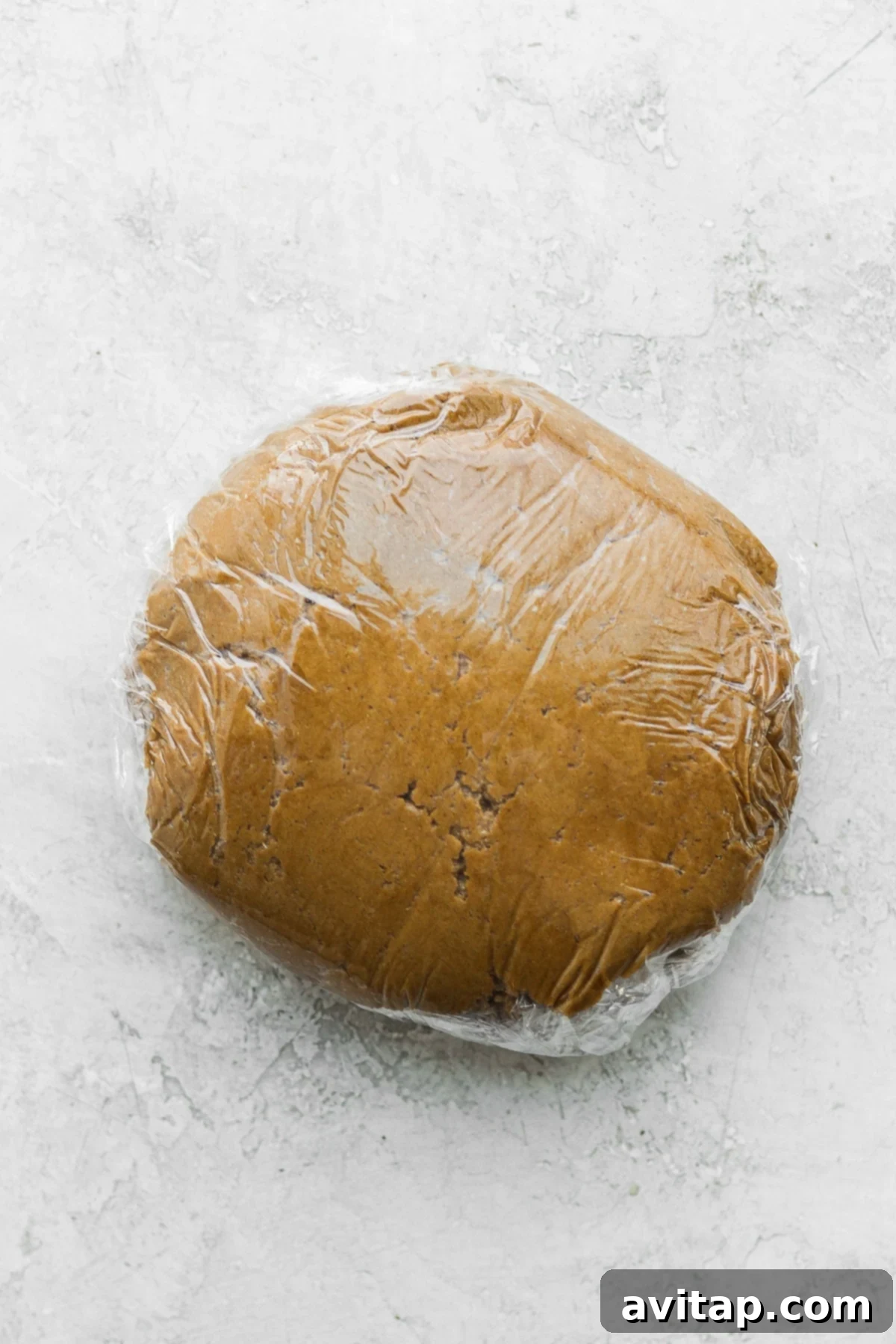 Gingerbread cookie dough, perfectly wrapped in plastic wrap and chilling, awaiting its transformation.