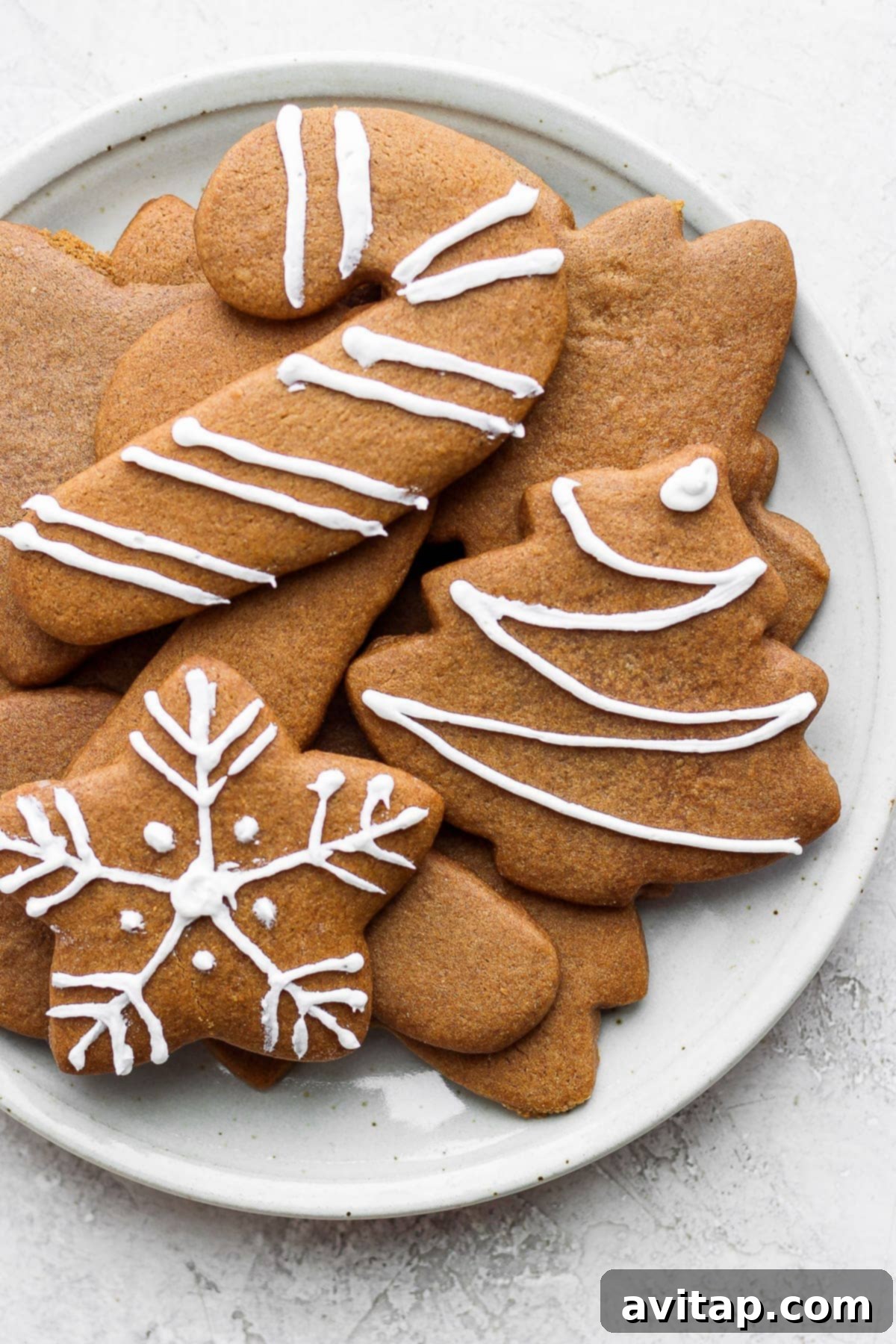 Beautifully decorated gingerbread cookies with white icing and sprinkles on a festive plate.