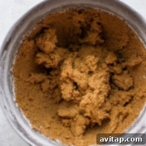 A metal mixing bowl filled with rich brown sugar, ideal for making delicious gingersnap cookies.