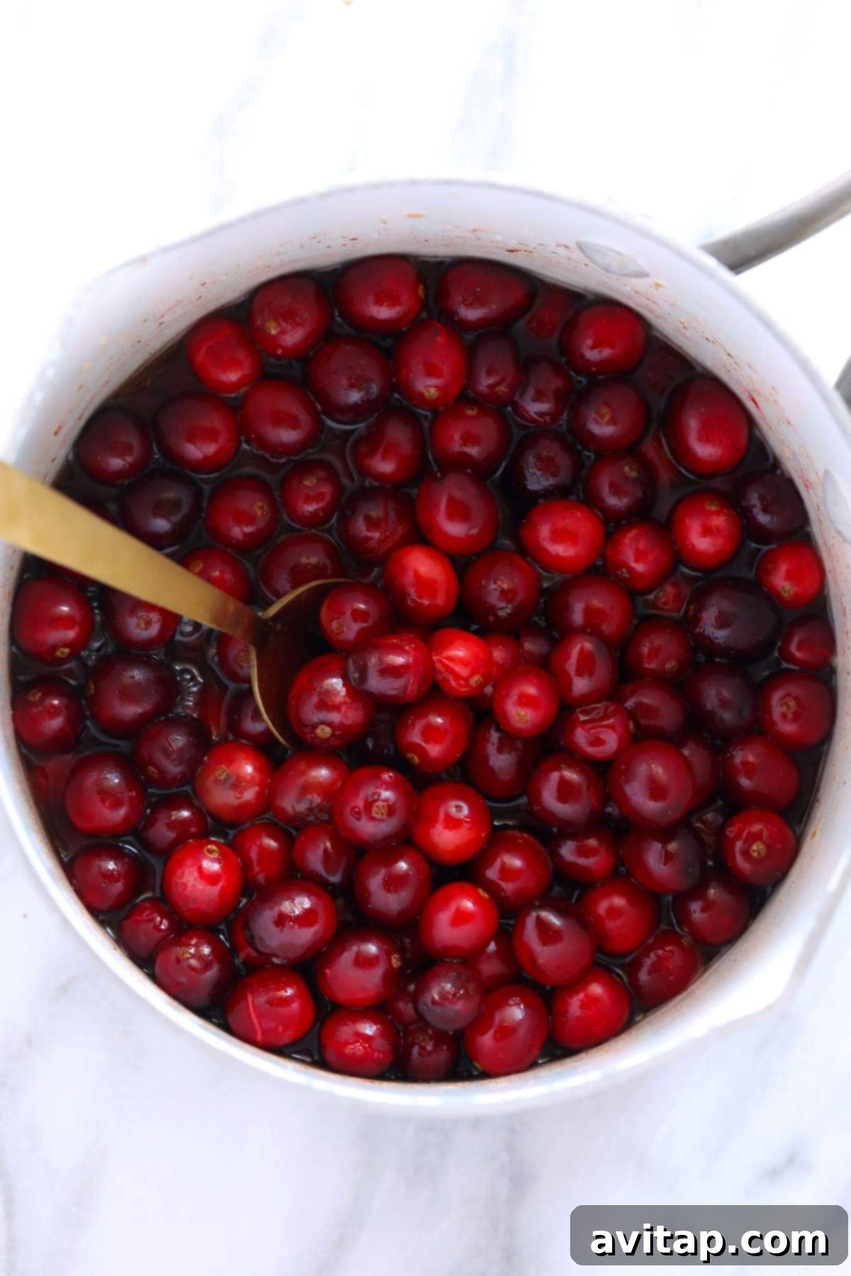 Whole fresh cranberries simmering in a saucepan on the stovetop, ready to transform into delicious sauce.