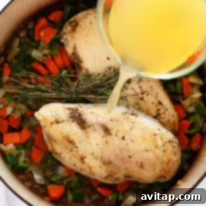 A person pouring olive oil into a pan with vegetables to prepare chicken wild rice soup.