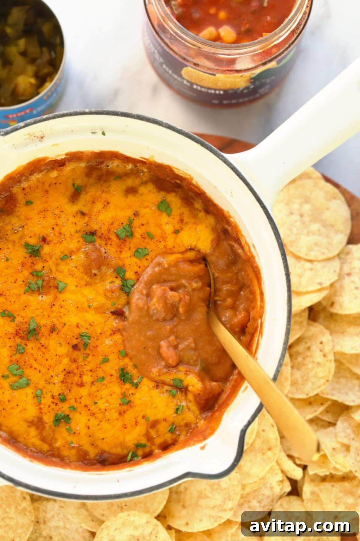 Beautifully baked cheesy bean dip in an oven-safe skillet, with perfectly melted, bubbly golden cheese on top, garnished with fresh cilantro, ready to be scooped.