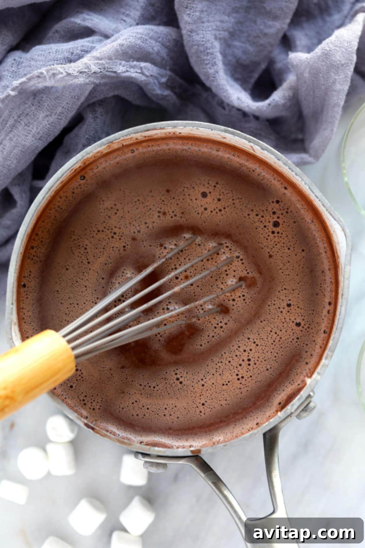 Spiked hot chocolate being whisked in a pot on the stove, showing the creamy texture.