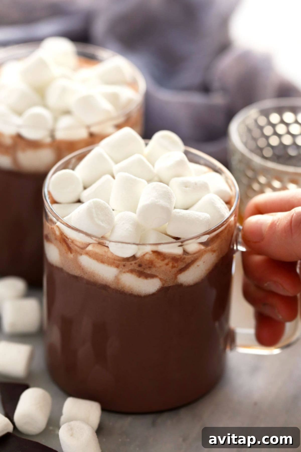 A close-up of spiked hot chocolate in a mug, generously topped with melted mini marshmallows.