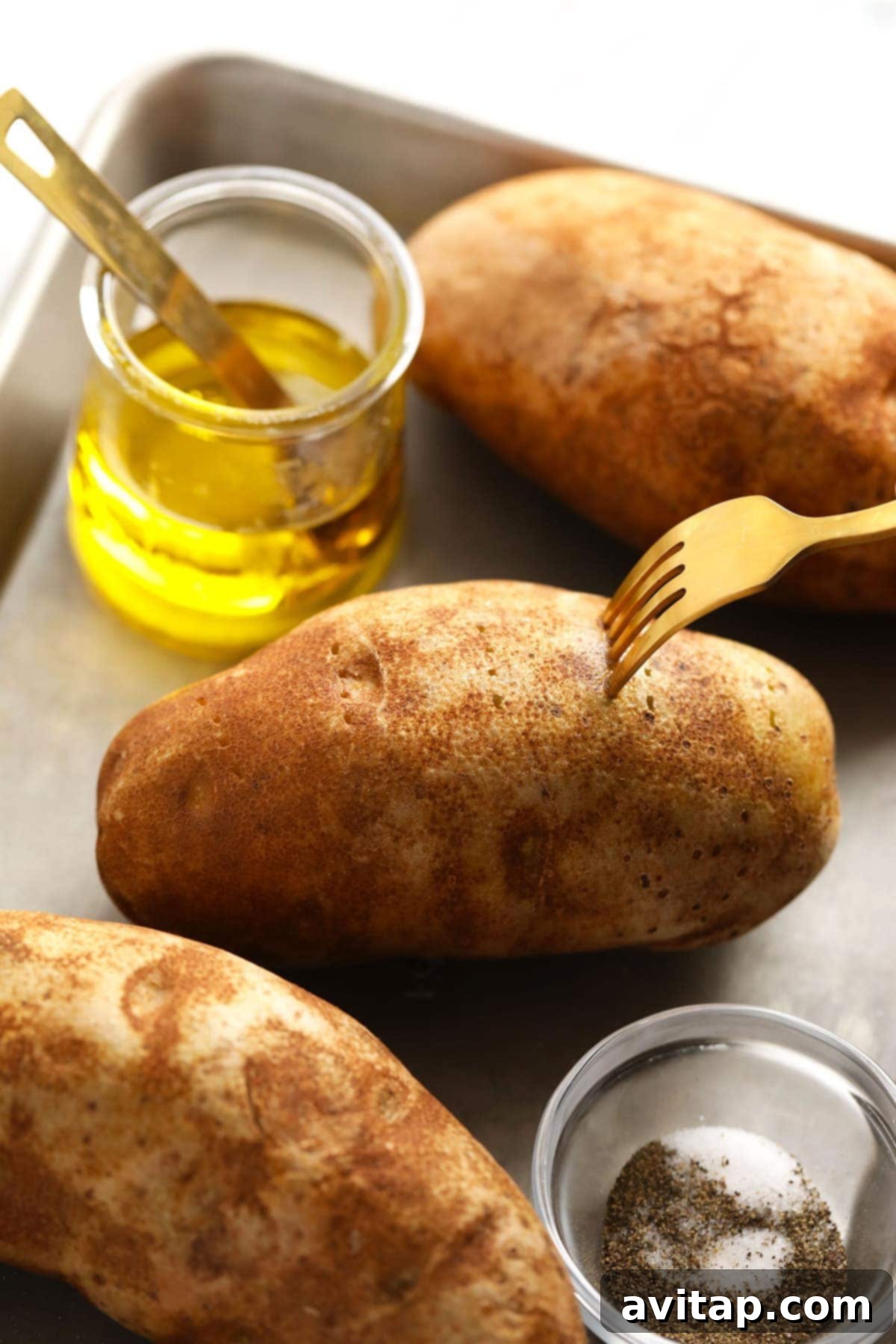 The Ultimate Crispy Fluffy Baked Potato 3 Close-up of a russet potato being massaged with olive oil, ready for seasoning.