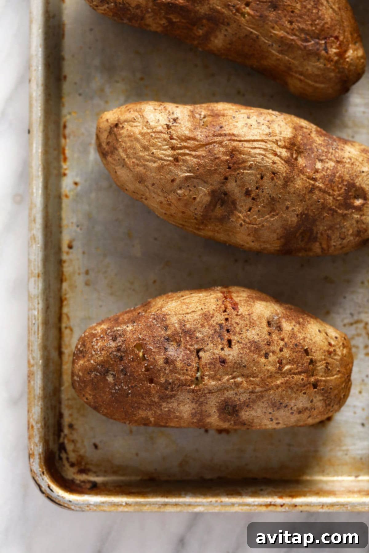 The Ultimate Crispy Fluffy Baked Potato 5 Two baked potatoes, perfectly golden and crispy, ready to be served.