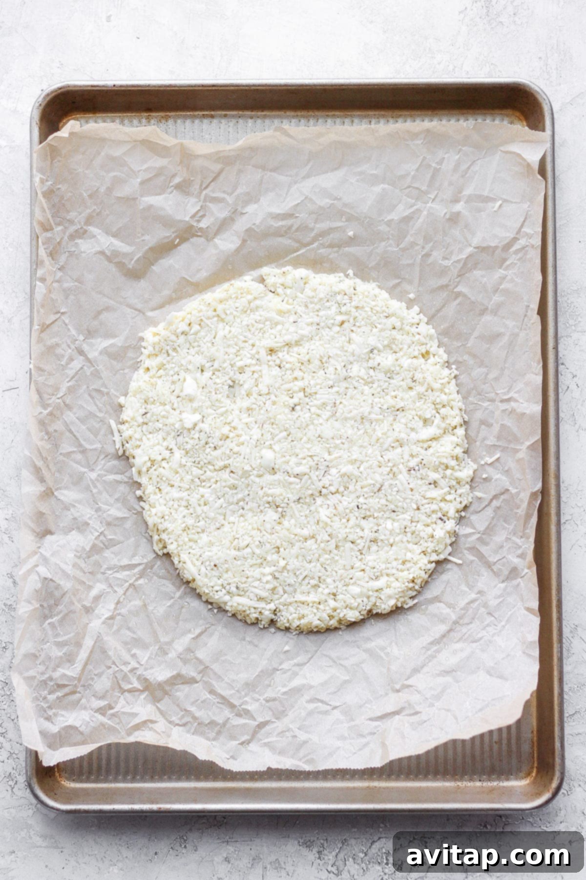 Veggie Powered Pizza Crust 7 The cauliflower pizza crust expertly shaped into a perfect circle on a baking sheet lined with parchment paper, ready for baking.