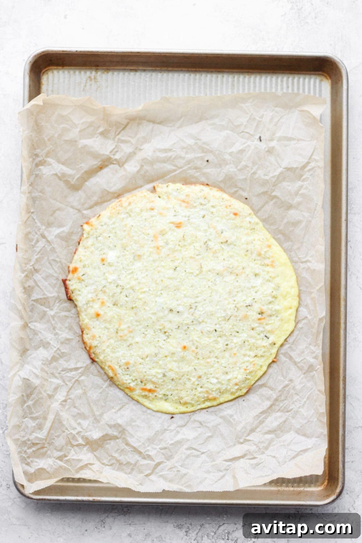 Veggie Powered Pizza Crust 8 A beautifully baked cauliflower pizza crust, golden brown and firm, resting on parchment paper after its initial bake.