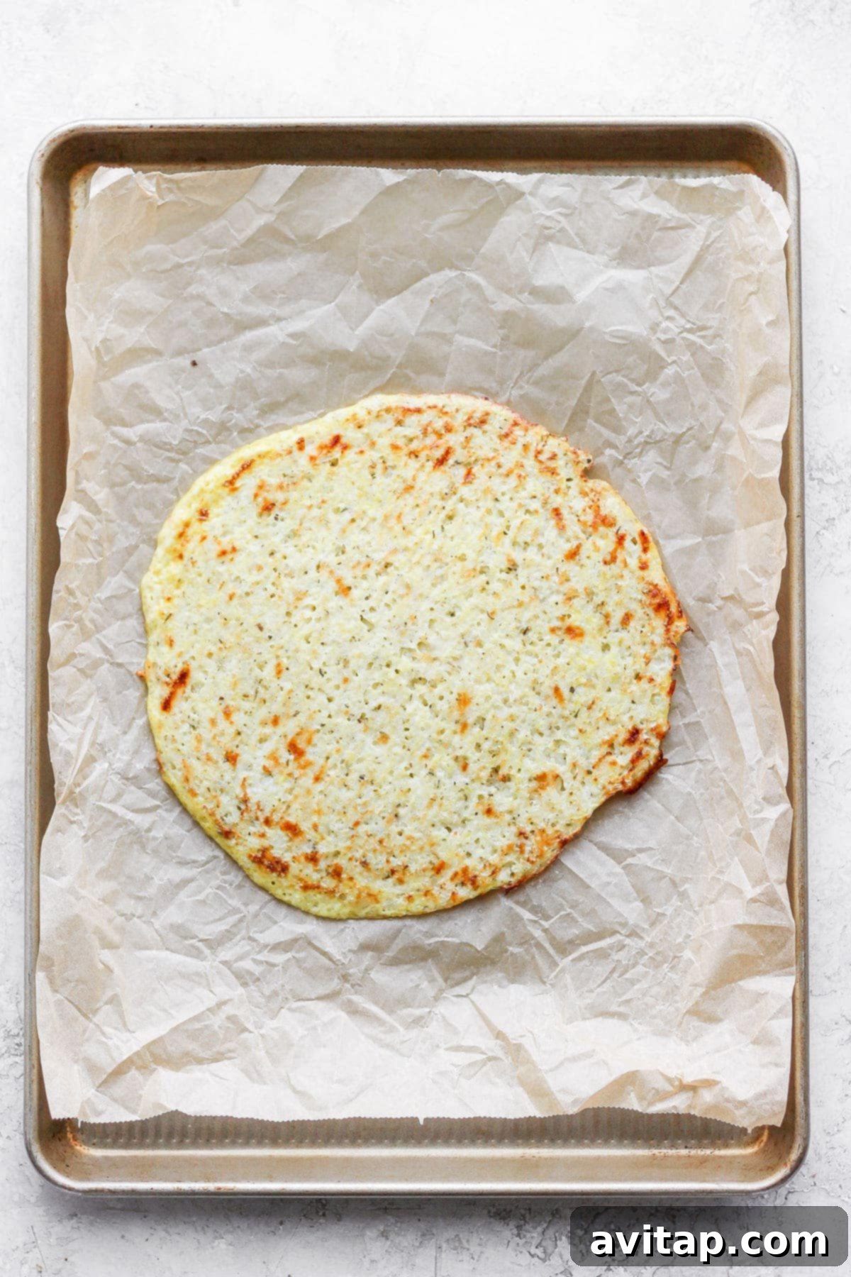 Golden-brown and crispy cauliflower pizza crust after being flipped and baked, ready for toppings.