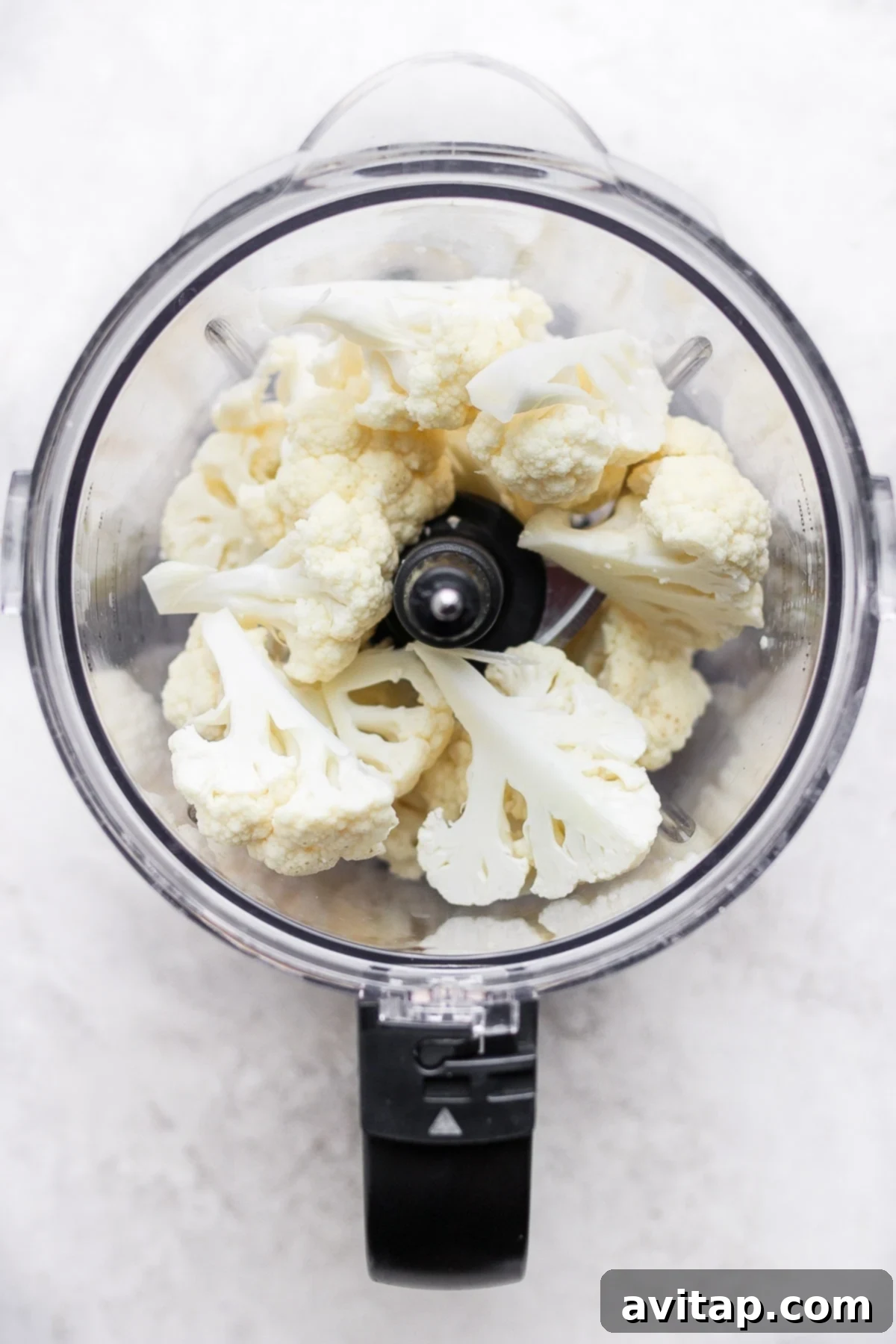 Raw florets of cauliflower in a food processor, ready for processing.