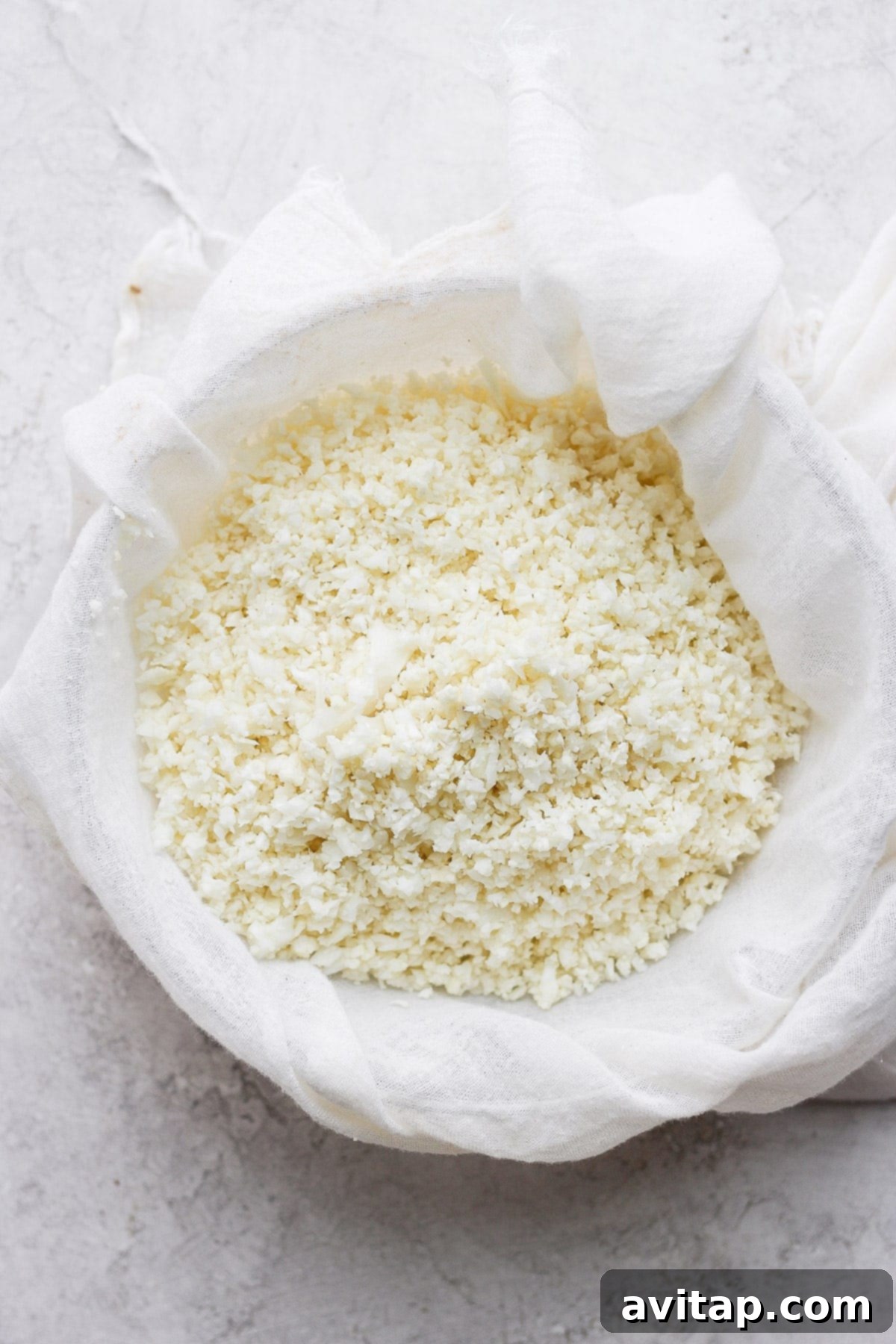 Cauliflower rice wrapped in a tea towel, with moisture being squeezed out.