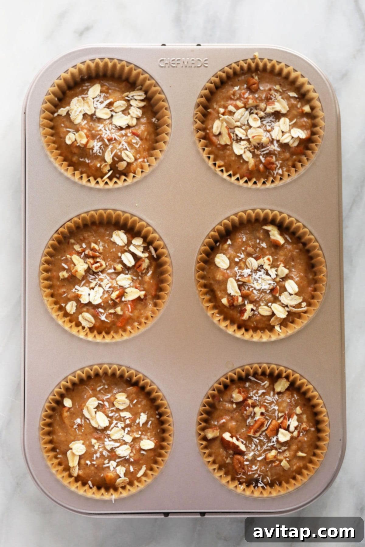 Muffin cups filled with morning glory muffin batter.