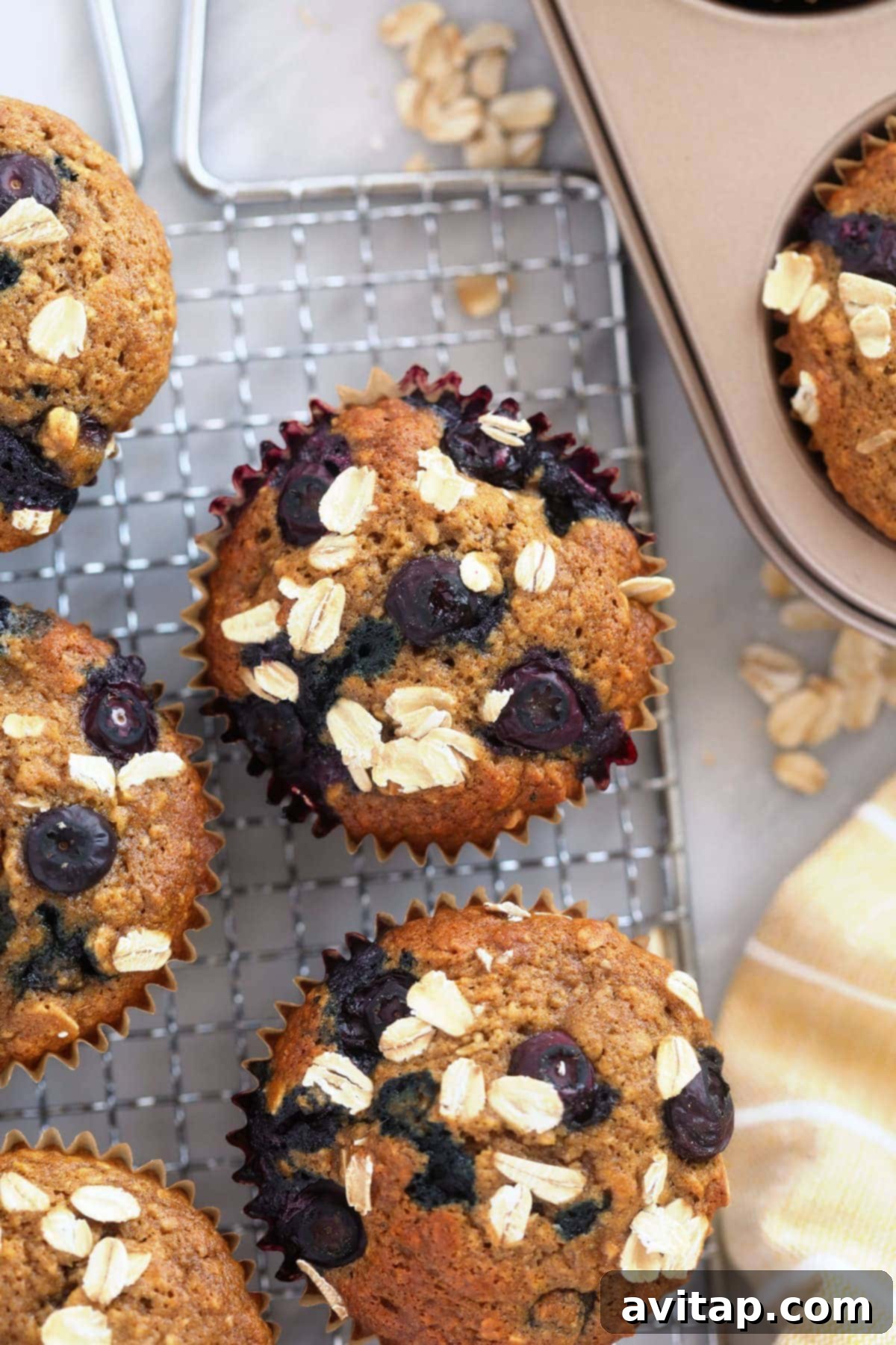 Deliciously fluffy blueberry oatmeal muffins topped with rolled oats, arranged enticingly on a cooling rack.