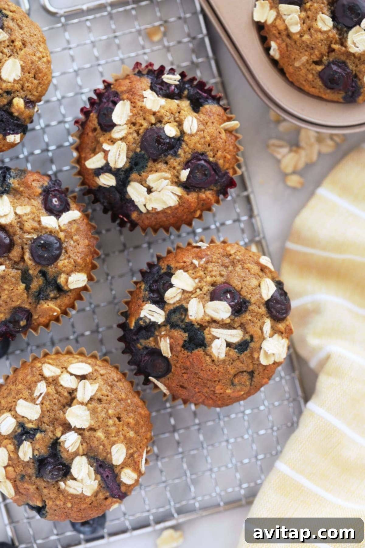 Freshly baked blueberry oatmeal muffins arranged neatly on a wire cooling rack, showcasing their golden-brown tops and fluffy texture.
