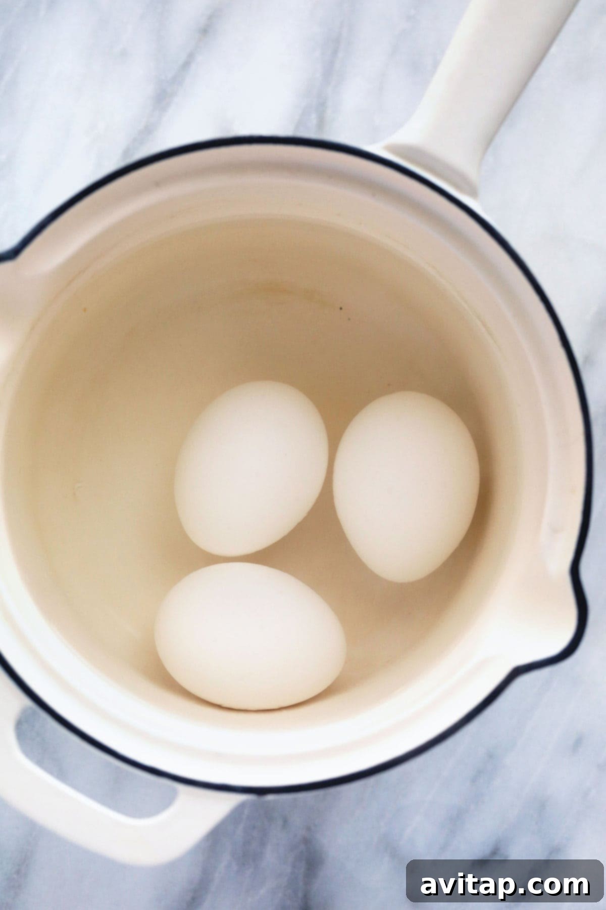 Eggs submerged in a pot of water, ready for boiling.