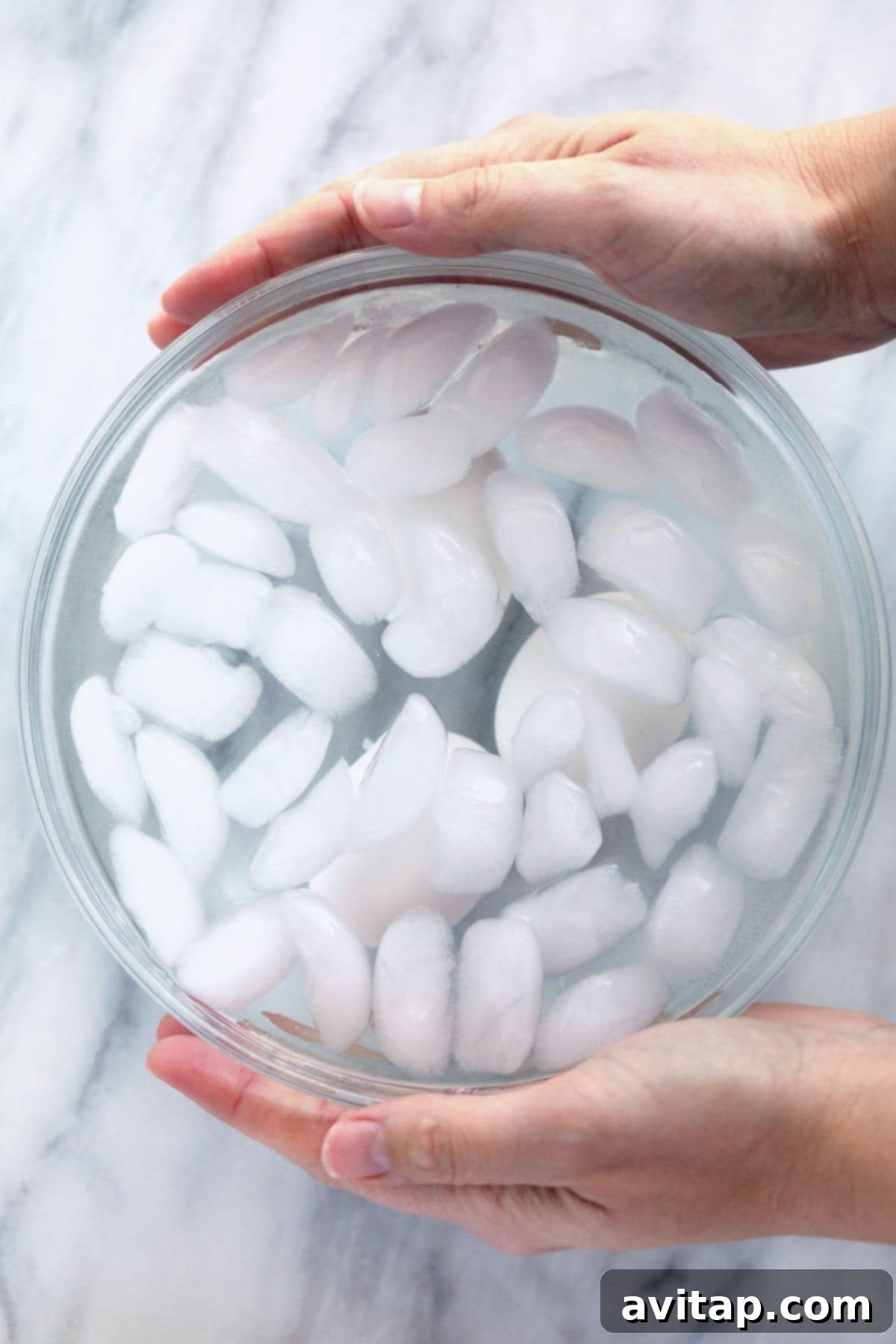 Hard boiled eggs cooling in a bowl of ice water to stop the cooking process.