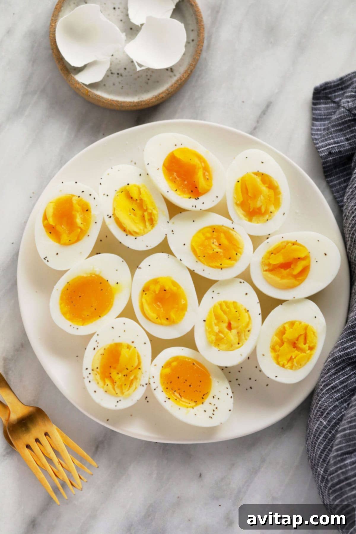 Perfectly halved hard boiled eggs served on a plate with forks, ready to eat.