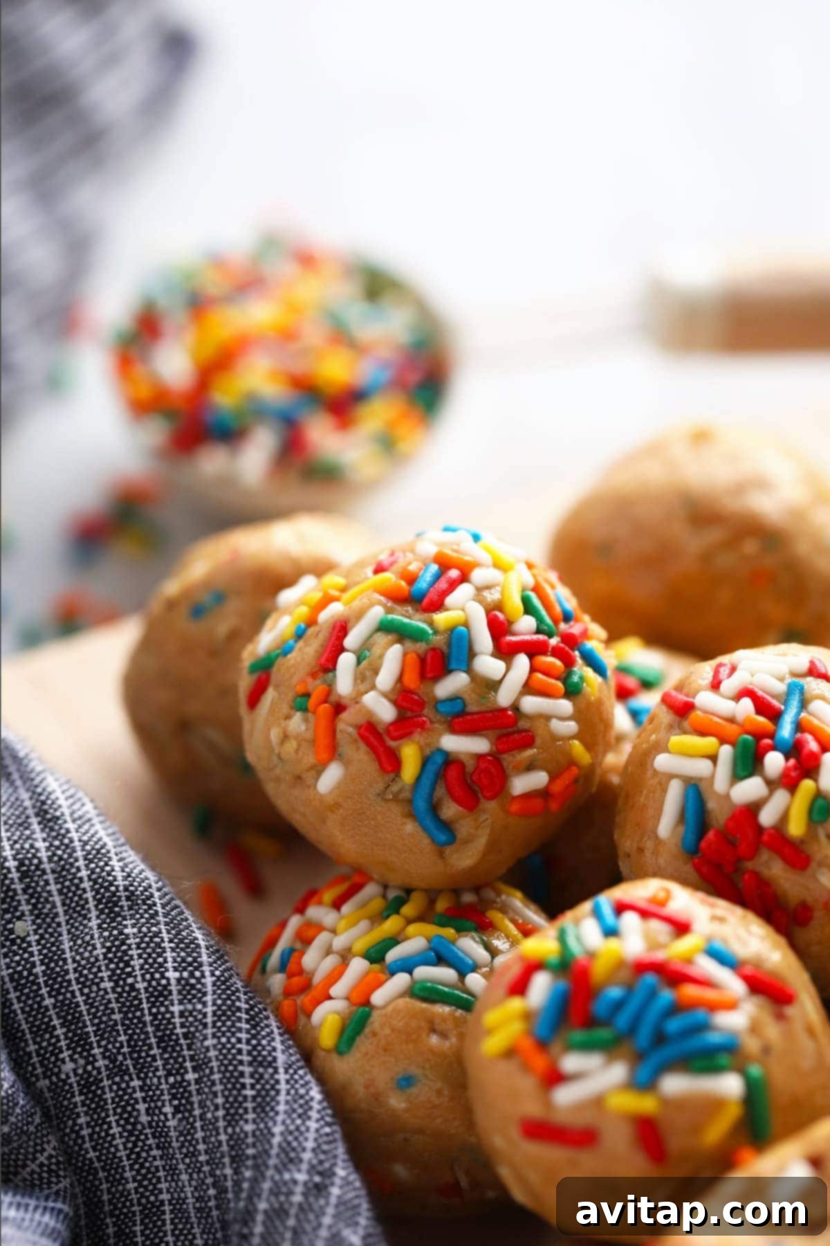 A plate full of delicious cake batter protein balls, generously covered in colorful rainbow sprinkles, making them a vibrant and inviting snack.