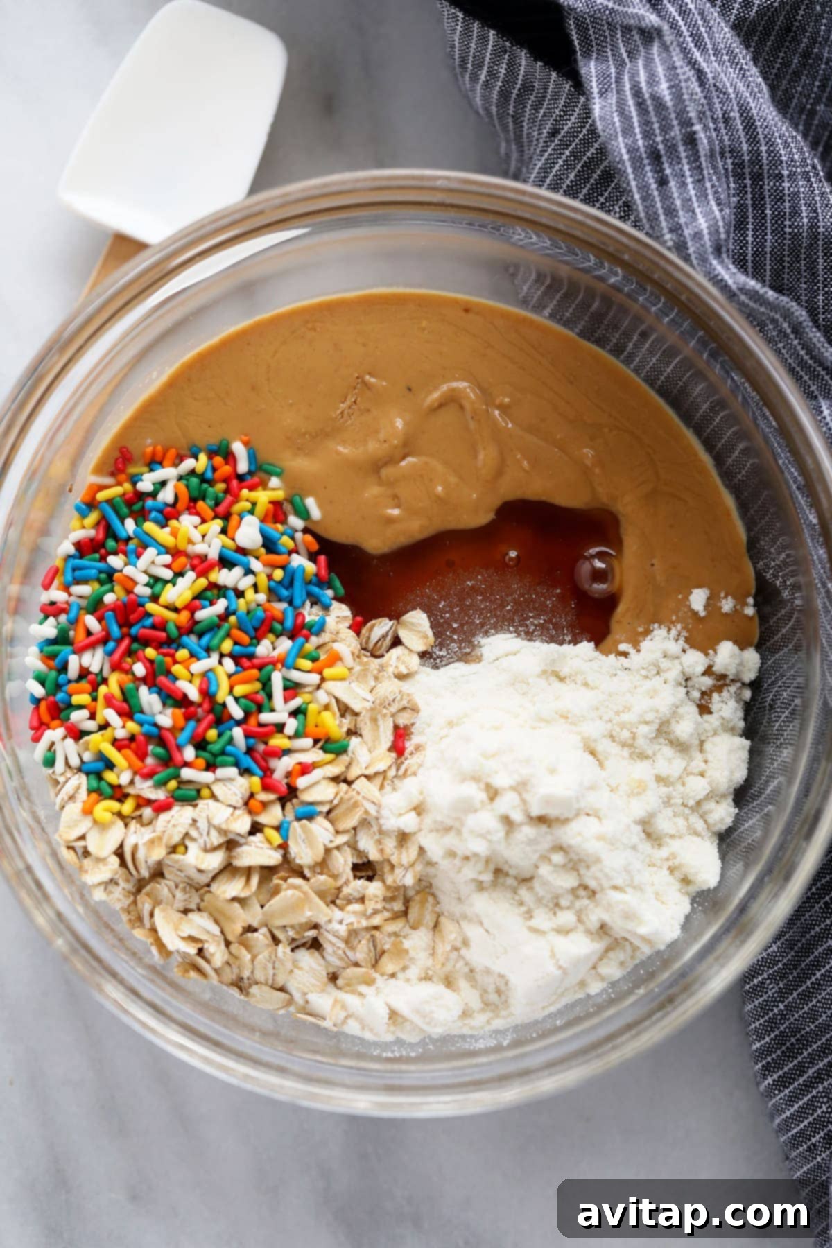 A bowl filled with all the essential ingredients for cake batter protein balls, ready to be mixed into a delicious dough.