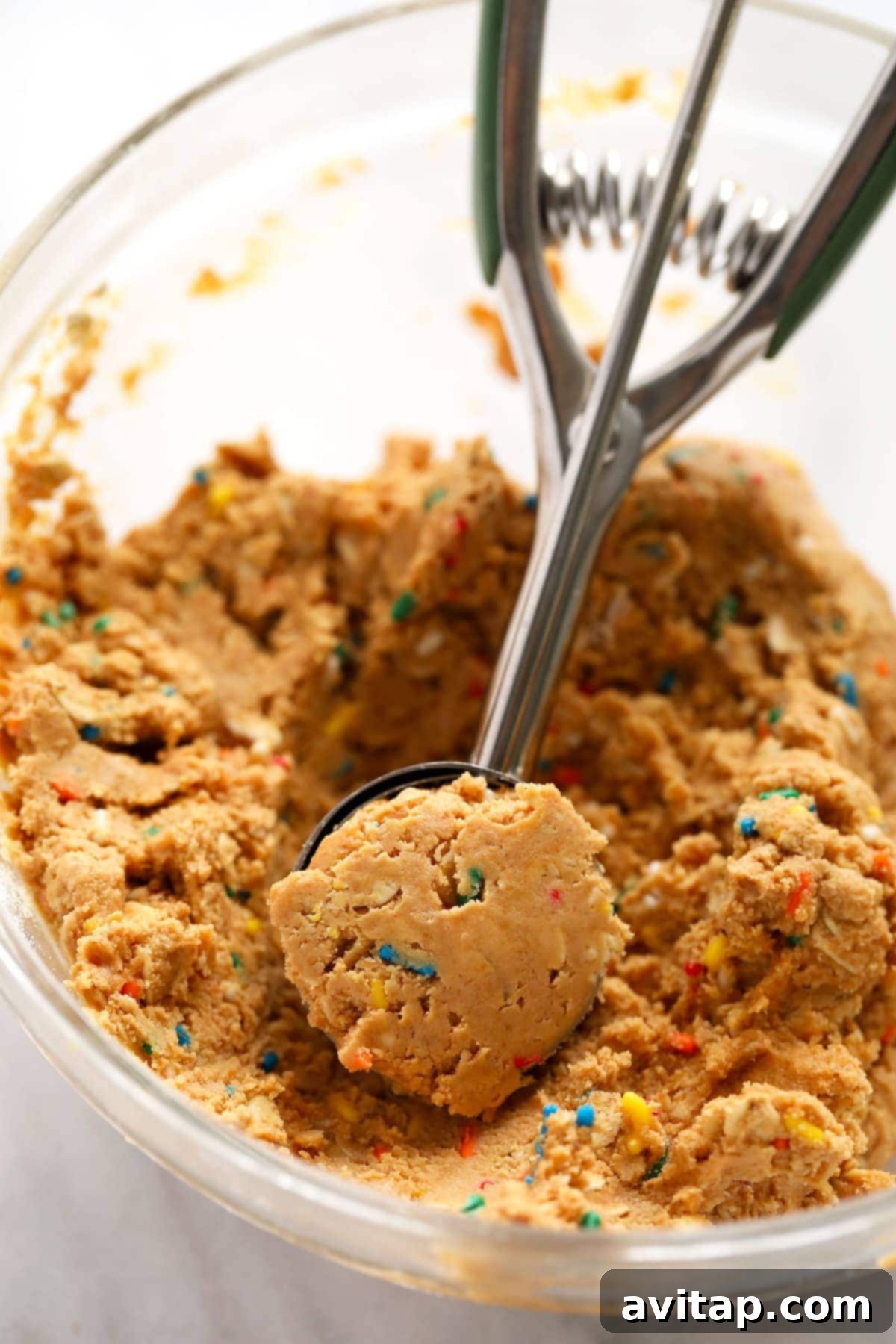 Close-up of cake batter protein ball dough being scooped and rolled into individual portions, showing the perfect texture before adding sprinkles.