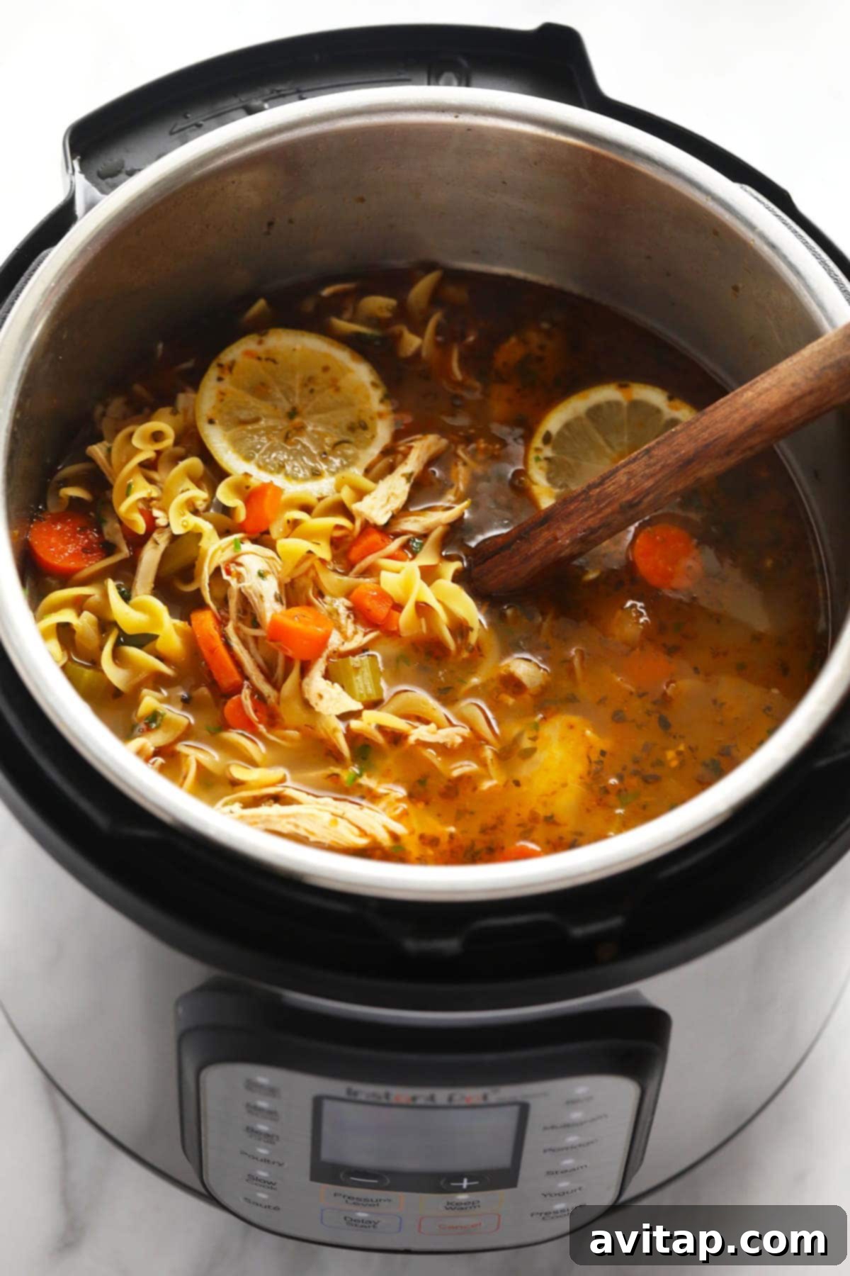 Instant Pot chicken Noodle Soup with a wooden spoon in the Instant Pot, ready to be served.