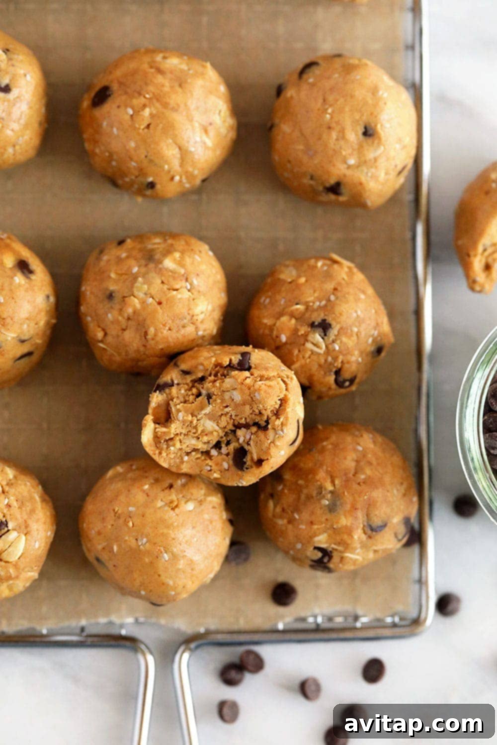 A close-up shot of several homemade peanut butter protein balls stacked in a pyramid, garnished with mini chocolate chips.